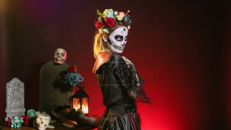Photo for Scary horror woman trying to lure with hand, reach and tempt victims in studio. Flirty la cavalera catrina model with mexican festival costume on holiday celebration, day of the dead. - Royalty Free Image