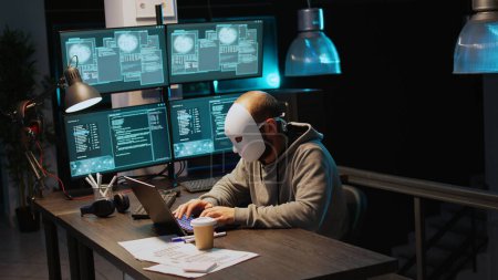 Impostor cibernético que usa servidores de bases de datos de hackeo de máscaras, hacker con capucha que irrumpe en el sistema informático y activa el virus para crear malware. Misterioso impostor robando big data. Disparo de mano.