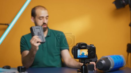 Foto de Vlogger revisión de grabación de acumuladores profesionales para equipos de videógrafos. Moderna tecnología tipo V-Lock, estrella de las redes sociales influencer distribución en línea - Imagen libre de derechos