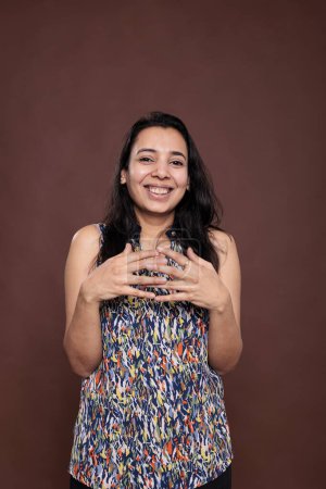 Foto de Mujer india sonriente entrelazando dedos retrato, mirando a la cámara. Señora feliz positivo de pie con expresión facial alegre, vista frontal estudio de tiro medio - Imagen libre de derechos