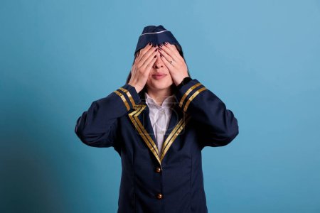 Photo for Stewardess covering eyes with hands, showing hear no evil gesture. Airplane flight attendant, looking at camera front view, no looking sign, three wise monkeys wisdom concept - Royalty Free Image