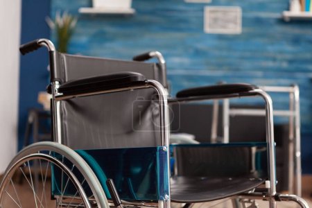 Foto de Silla de ruedas colocada para personas con discapacidad en una habitación vacía del hogar de ancianos. Espacio luminoso con andador de apoyo y asistencia en el centro de vida asistida de ancianos, rehabilitación de salud. - Imagen libre de derechos