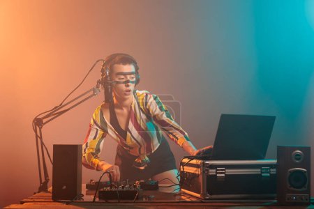 Female artist mixing techno music with turntables, musical performer playing sounds to produce melody at mixer. Performing song with electronics equipment and audio instrument, crazy make up.
