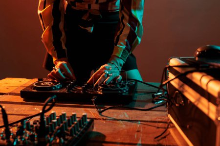 Photo for Woman performer mixing techno music on turntables, playing record mix sounds on audio dj instrument and stereo equipment. Enjoying nightclub party with stage production in studio. - Royalty Free Image