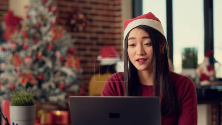 Photo for Employee attending business meeting videocall on laptop with webcam during christmas season in festive decorated office. Talking on online remote videoconference, celebrating xmas eve. - Royalty Free Image