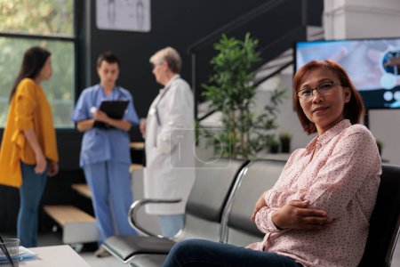 Photo for Portrait of old asian patient sitting in hospital waiting area having checkup consultation with medic. Woman attending medical appointment with physician to cure illness and get treatment. - Royalty Free Image