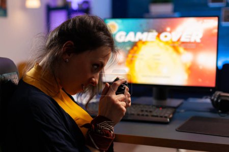 Foto de Se acabó el juego para el jugador jugando videojuegos en una computadora poderosa durante la noche en un estudio de juegos en casa. Mujer streaming de videojuegos en línea para el torneo de esport en la habitación con luces de neón - Imagen libre de derechos