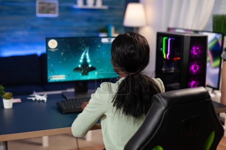 Photo for Pro gamer woman sitting at gaming desk playing space shooter videogames for online championship. Concentrated player using professional RGB computer equipment in home studio. Esport games - Royalty Free Image