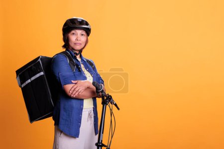 Photo for Portrait of take away delivery employee carrying thermal takeout food backpack, delivering pizza meal from restaurant. Smiling bicyclist wearing helmet during deliver job, home delivery service - Royalty Free Image