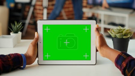 Photo for Young adult holding digital gadget with horizontal green screen, looking at blank background on modern device. Analyzing isolated chroma key display and mock up template. Close up. - Royalty Free Image