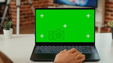 Photo for Young adult analyzing greenscreen display on personal computer, looking at isolated mockup template and working with chroma key. Using blank copyspace on laptop at home. Close up. - Royalty Free Image