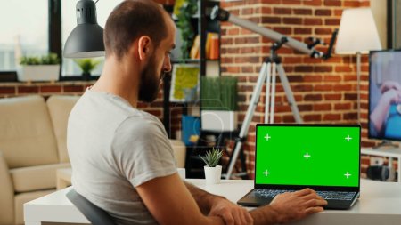 Photo for Modern manager looking at laptop with greenscreen display and analyzing blank chroma key template on portable computer. Checking isolated background and mockup copyspace on pc. - Royalty Free Image
