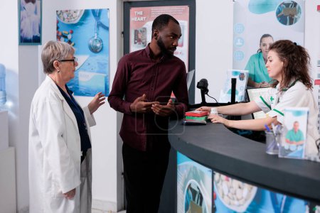 Photo for African american customer standing at pharmacy counter discussing medical prescription with pharmacist before start buying drugs. Drugstore employee offering assistance service, medicine support - Royalty Free Image