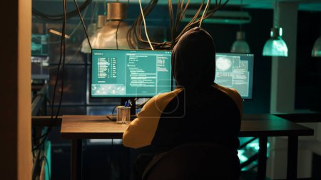 Téléchargez les photos : Hackers using network vulnerability to exploit security server, trying to break computer system at night. People working with multiple monitors to hack software, illegal hacktivism. - en image libre de droit