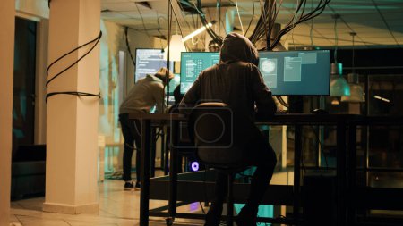 Foto de Woman hacker planning phishing and espionage at night, trying to break server firewall for cryptojacking or cyberbullying. Criminal hacking network system on computer, anonymous. - Imagen libre de derechos