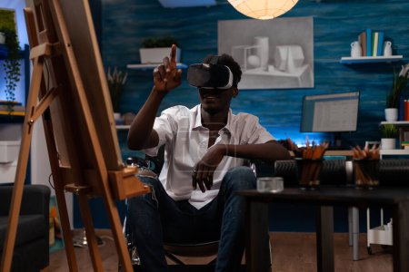 Téléchargez les photos : African american art student using virtual reality goggles to navigate online universe and create drawing masterpiece. Modern artist browsing in metaverse looking new sketching techniques. - en image libre de droit