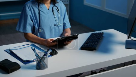 Assistenzärzte, die Krankheitssymptome von Patienten analysieren, berichten am Computer über den Vergleich mit medizinischer Expertise auf Tablets, die bis spät in die Nacht im Krankenhausbüro arbeiten. Medizinischer Service und Konzept