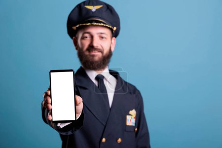 Téléchargez les photos : Airplane capitan showing smartphone with blank white screen close up, phone advertising product mockup with copy space. Plane pilot holding telephone with empty display for app promo ads - en image libre de droit