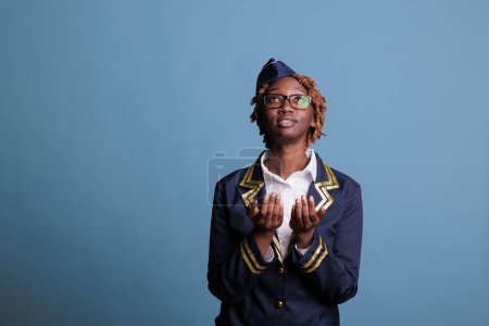 Photo for Medium shot studio, portrait of curly hair, wearing glasses, uniformed, african american woman looking up. Female young stewardess wishing, longing. Air hostess praying. - Royalty Free Image