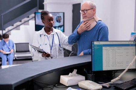 Photo for Senior patient with medical neck collar having checkup visit consultation with doctor in hospital waiting area. Man with cervical foam and medic discussing about symptoms and medication treatment - Royalty Free Image
