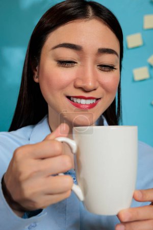 Téléchargez les photos : Professional woman drinking coffee in modern workspace preparing for a busy day at work. Businesswoman concentrating on enjoying a hot drink in the morning at the office. - en image libre de droit