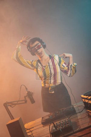 Foto de Playful artist sticking tongue out and fooling around, using turntables to mix techno music and act silly. Funky DJ woman being laid back and relaxed while she plays with stereo insturment. - Imagen libre de derechos