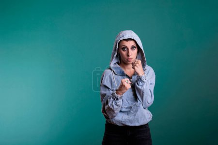 Foto de Aggressive woman clenching fists and showing raised knuckles on camera, feeling angry while doing air punches in studio. Furious violent female preparing to fight, standing over isolated background - Imagen libre de derechos