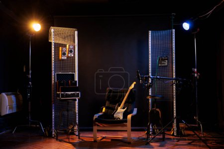 Foto de Empty music recording studio with guitar on chair, next to amps, sound amplifier equipment. Nobody in professional dark rock room, performance speaker - Imagen libre de derechos