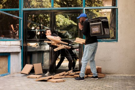 Téléchargez les photos : Confused office food delivery customer catching falling pizza boxes pile, scared courier dropping order outdoors. Careless african american man delivering fastfood packages stack - en image libre de droit