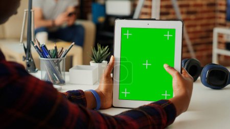 Photo for Young student using greenscreen template on digital tablet, analyzing isolated copyspace display on gadget. Working with blank chroma key mockup and portable wireless device. Close up. - Royalty Free Image
