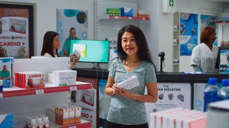 Téléchargez les photos : Femme client à la recherche de médicaments dans le magasin de pharmacie, en regardant les étagères remplies de boîtes de pilules et de bouteilles. Drugstore client lisant des emballages de médicaments, produits pharmaceutiques. - en image libre de droit