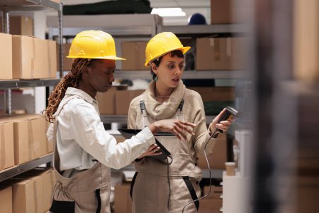 Téléchargez les photos : Diverses femmes gérantes d'entrepôt scannant des colis pour la surveillance des stocks. Employés d'entrepôt utilisant le dispositif de scanner de code-barres pour l'inventaire de fret dans le logiciel de compagnie maritime - en image libre de droit