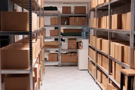 Foto de Cardboard boxes stacks on empty delivery service warehouse room shelves. Goods packages on racks structure in factory industry logistic department storehouse with nobody inside - Imagen libre de derechos