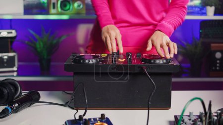 Photo for Dj artist mixing elenctronic sound with techno using turntables, performing new albun for fans, enjoying playing music during concert in club at night. Professional audio equipment. Close up - Royalty Free Image
