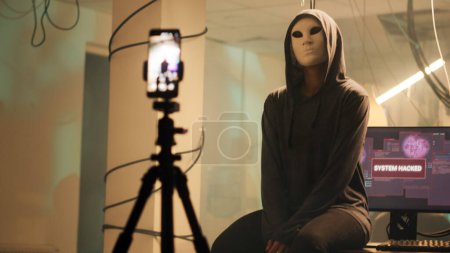 Photo for Dangerous thief filming ransomware video to receive money, stealing important data and broadcasting live threat. Mysterious hacker with anonymous mask doing illegal activity. Handheld shot. - Royalty Free Image