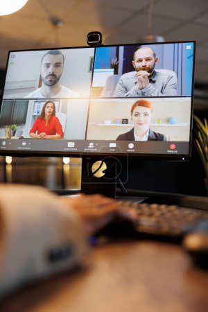 Téléchargez les photos : Manager explaining company investment strategy to remote colleagues during online videocall meeting conference. Diverse corporate team working late at night in startup office. Business concept - en image libre de droit