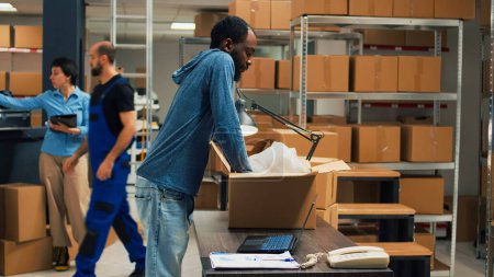 Foto de African american owner taking products from storage racks to prepare merchandise order in warehouse. Employee selling goods and working on business development, retail delivery. - Imagen libre de derechos