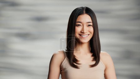 Photo for Asian beauty model posing for skincare ad in studio, woman with radiant and luminous skin feeling confident. Beautiful positive girl creating empowering, uplifting bodycare campaign. - Royalty Free Image