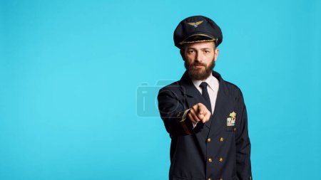 Foto de Airplane pilot in uniform pointing at camera and choosing, saying i want you for commercial flights cabin aircrew. Young male captain flying plane and acting positive, feeling confident. - Imagen libre de derechos