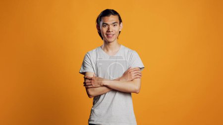 Photo for Casual asian man posing on studio background, young adult being confident and carefree on camera. Athletic male model acting positive with cool style, hipster having fun for entertainment. - Royalty Free Image