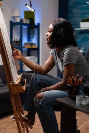 Photo for Woman with hand drawing skills starting sketch with colored pencils at art creation place. African american sketching artist putting finishing touches on handmade artwork in studio. - Royalty Free Image