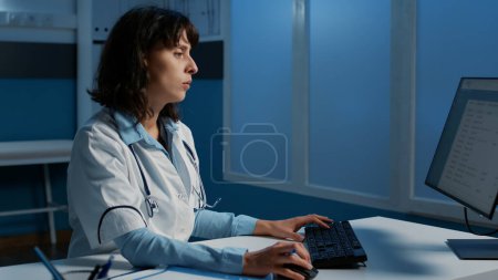 Photo for Physician doctor sitting at desk working night shift at medical expertise on computer in hospital office, planning patient medication treatment to help cure disease. Medicine service and concept - Royalty Free Image