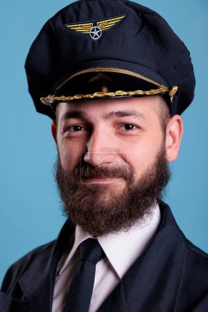 Photo for Aircraft captain wearing uniform and hat portrait, confident plane pilot standing with crossed arms, looking at camera. Smiling civil aviator with badge on professional suit - Royalty Free Image