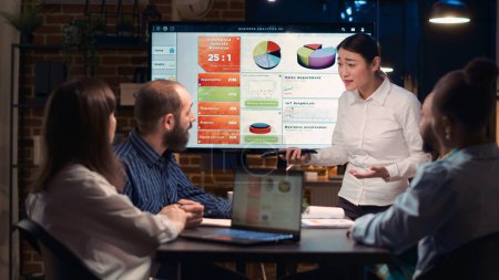 Photo for Project manager presentation, asian company employee explaining analytics research results in business meeting, showing statistics diagrams on digital board. Marketing revenue report visualization - Royalty Free Image