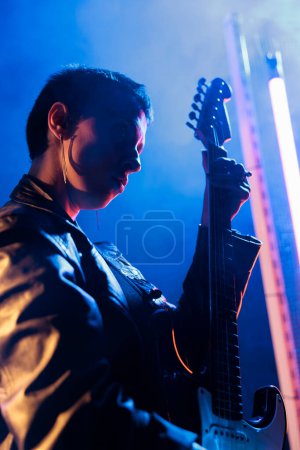 Photo for Portrait of rockstar performer playing at electric guitar adjusting sound before rock concert, composer working at heavy metal song. Superstar woman with rebel style preparing punk album in studio - Royalty Free Image