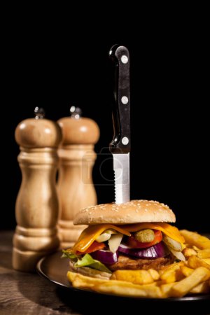 Téléchargez les photos : Des cheesburgers maison classiques sur plaque noire et fond à côté des frites. Restauration rapide. Collation malsaine - en image libre de droit