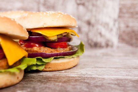 Foto de Delicious fresh home made burgers on wooden plate. Fast food. Unhealthy snack - Imagen libre de derechos