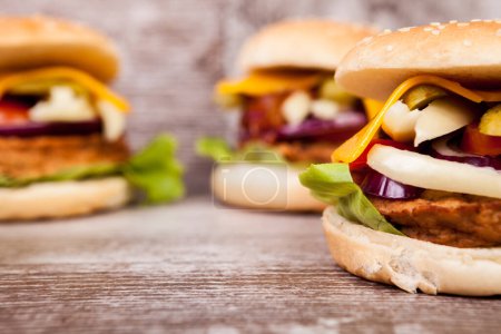 Foto de Primer plano de Deliciosas hamburguesas caseras en plato de madera. Comida rápida. Snack malsano - Imagen libre de derechos