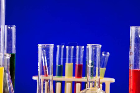 Téléchargez les photos : Laboratoire de chimie avec des liquides colorés sur une table sur fond bleu. Verrerie et matériel de biologie - en image libre de droit