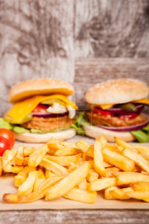 Photo for Delicious home made sandwich burgers on wooden plate next to fries. Fast food. Unhealthy snack - Royalty Free Image